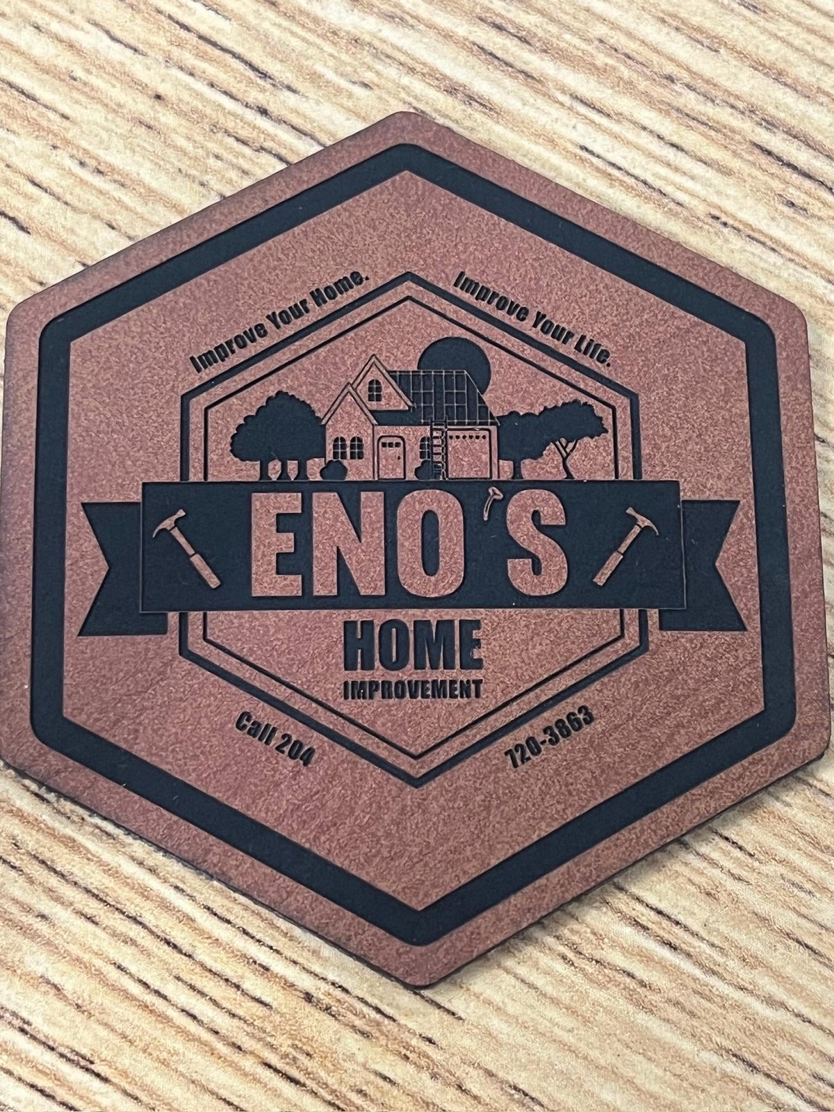 Hexagonal leather coaster laser-engraved with a custom home improvement business logo